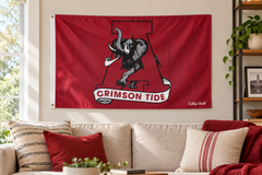 Alabama College Vault elephant and block A flag above a fan-room sofa — lifestyle visualization
