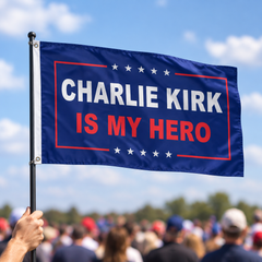 Charlie Kirk Is My Hero flag on a pole at an outdoor rally