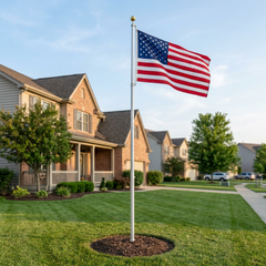 Silver telescoping flagpole with gold ball and American flag displayed in a landscaped residential front yard.