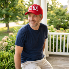 Red MAGA embroidered hat worn in a casual outdoor porch setting