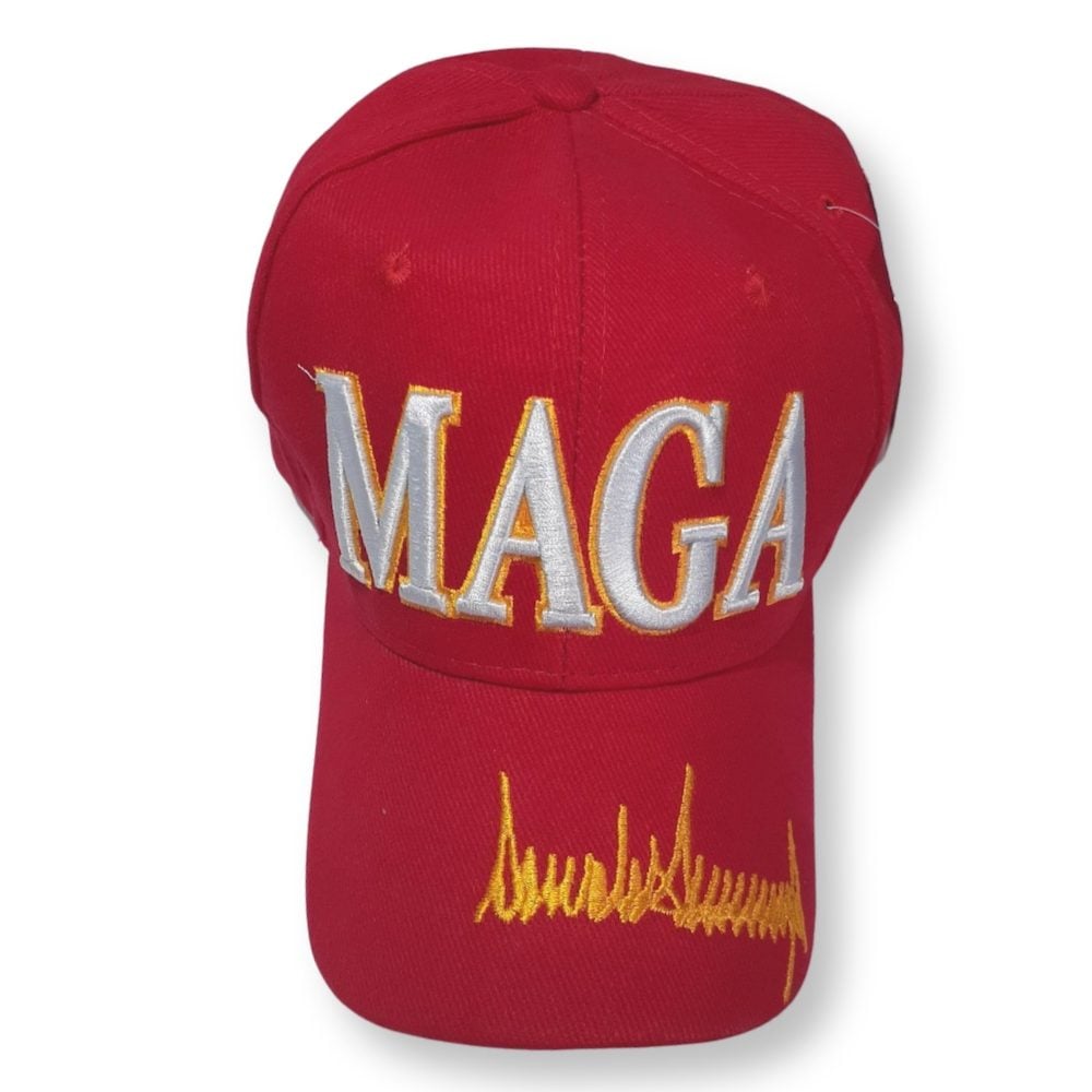 A red baseball cap with 'MAGA' embroidered in white and gold on the front and a signature in gold at the side.